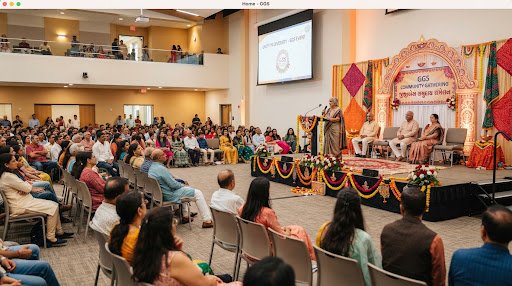 A large community gathering listening to a speaker on stage decorated with Gujarati cultural motifs.